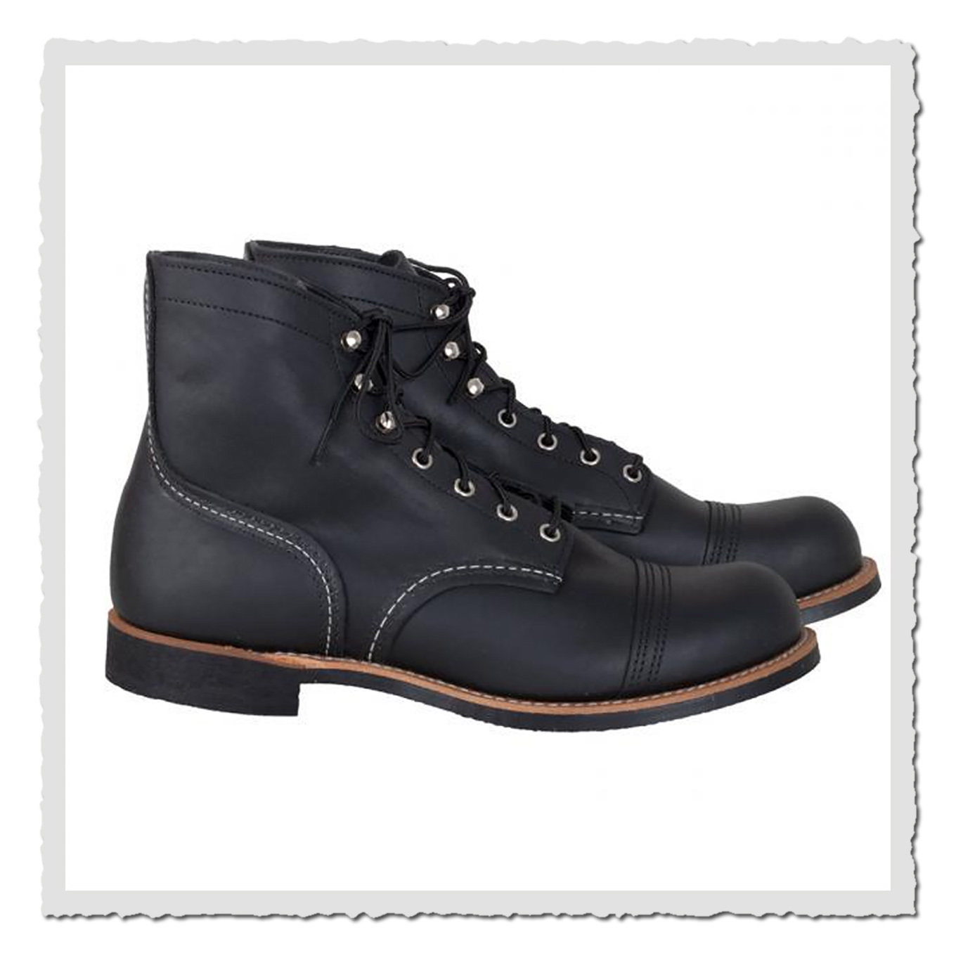 Ein Paar schwarze Lederboots seitlich fotografiert, weiße Studiofläche, Metallösen und runde Kappen sichtbar.